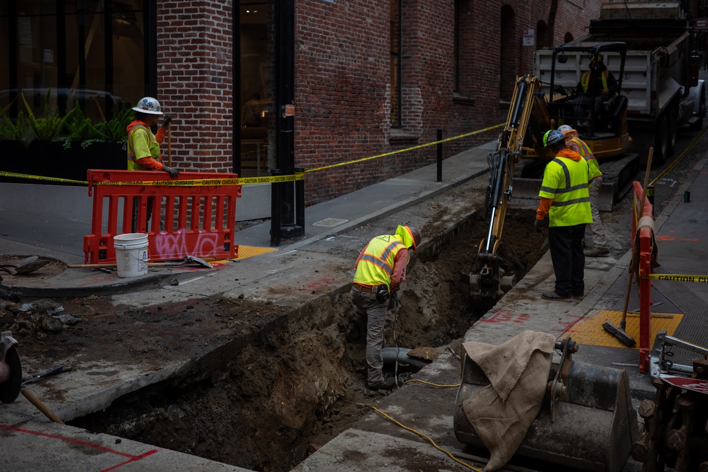 Utility crew opening a trench along a city street with a mini excavator